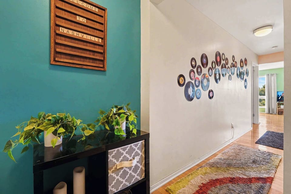 Step inside through a welcoming entryway highlighted by Nashville-inspired vinyl record wall art, warm hardwood floors, and inviting décor that sets the stage for a memorable Music City stay.