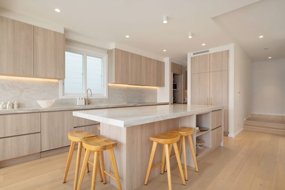 Sleek light-wood kitchen with marble island and seating for four.