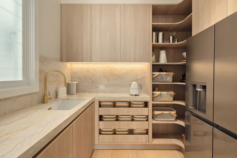Sleek, organized kitchen with marble surfaces, gold taps, and premium fridge with cold water and icemaker