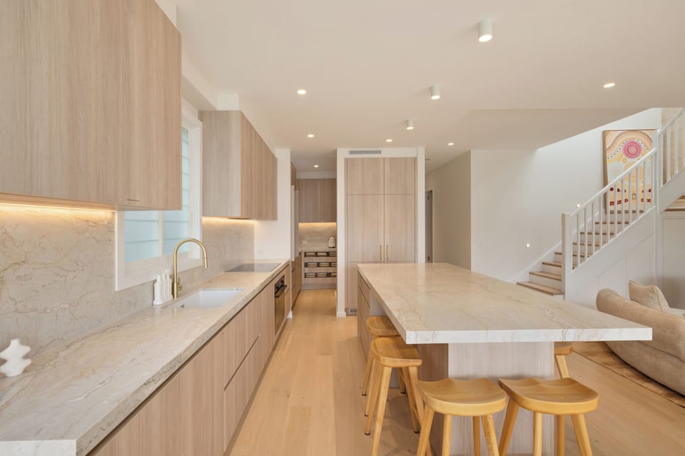 Sleek chef’s kitchen with stone island seating in open-plan setting