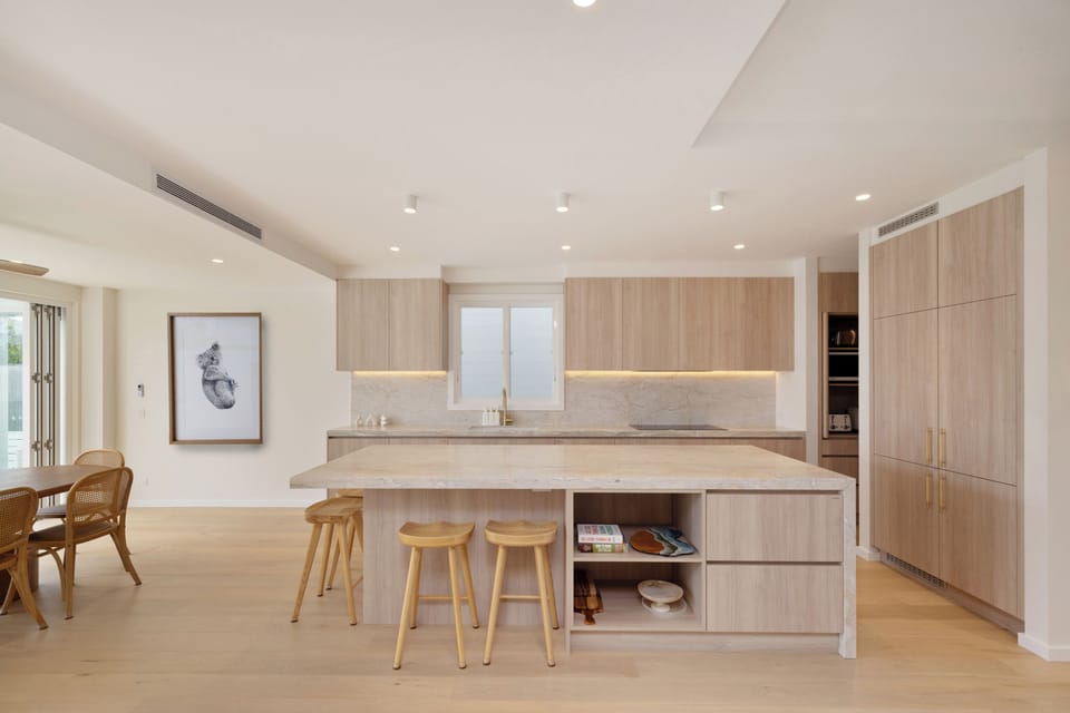 Chef’s kitchen with island seating, sleek wood cabinets, and abundant natural light