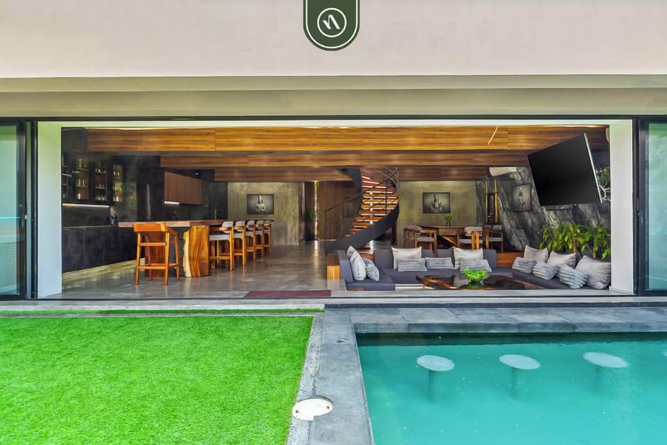 Expansive open-air living area with a seamless flow to the pool. Features a cozy lounge, sleek bar seating, and modern design—perfect for entertaining or unwinding in a stylish, tropical-inspired setting.