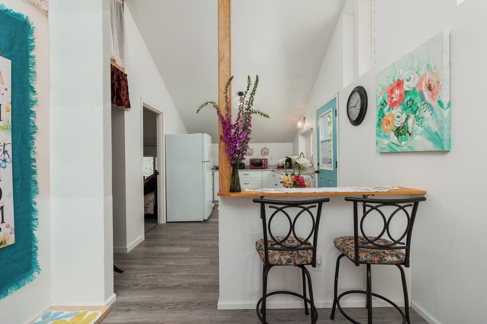 Bright, airy living space with vaulted ceilings and charming breakfast bar where you can sip morning coffee surrounded by cheerful artwork and thoughtful touches.