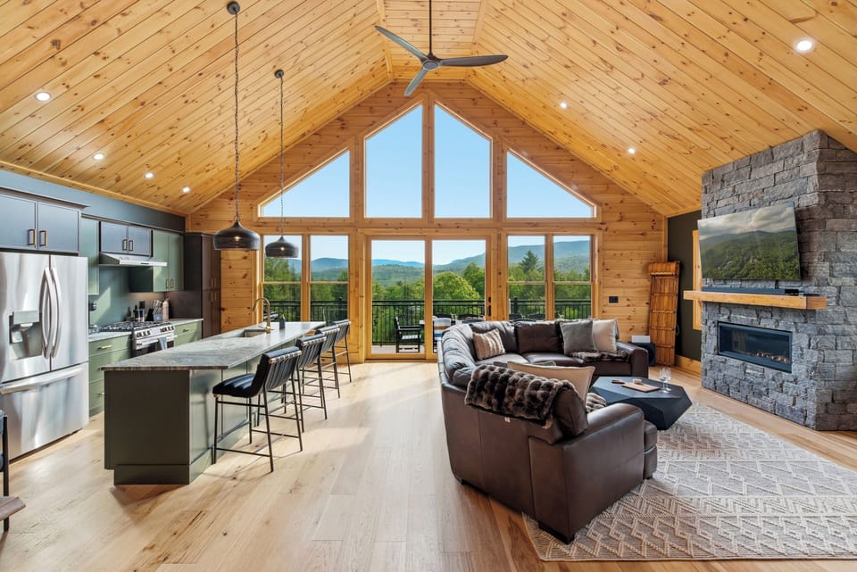 Enjoy an airy open-concept layout connecting the kitchen, dining, and living spaces beneath vaulted wood ceilings.