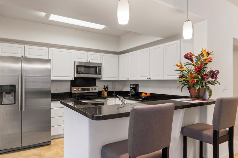 The well-equipped kitchen features granite countertops, stainless steel appliances, and bar seating for casual dining.