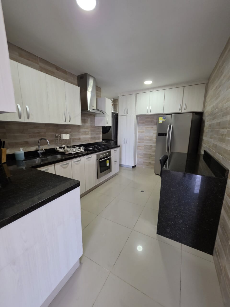 Modern kitchen with granite counters, gas range, and stainless fridge