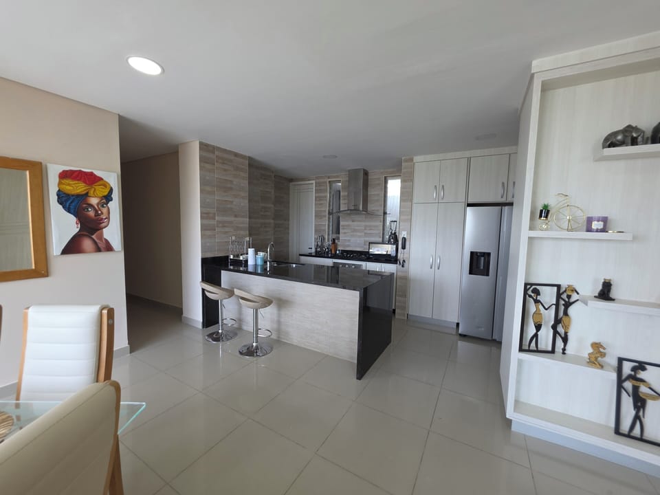 Sleek open kitchen with island, stainless fridge & chic decor