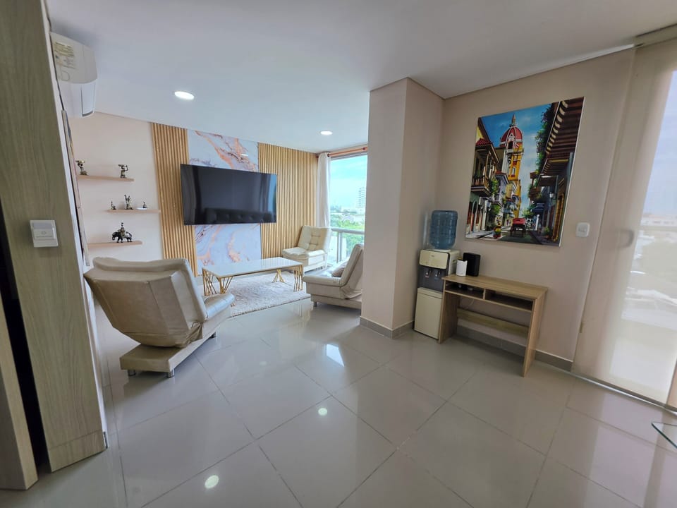Bright modern lounge with balcony views, big TV, AC, and coffee/water bar