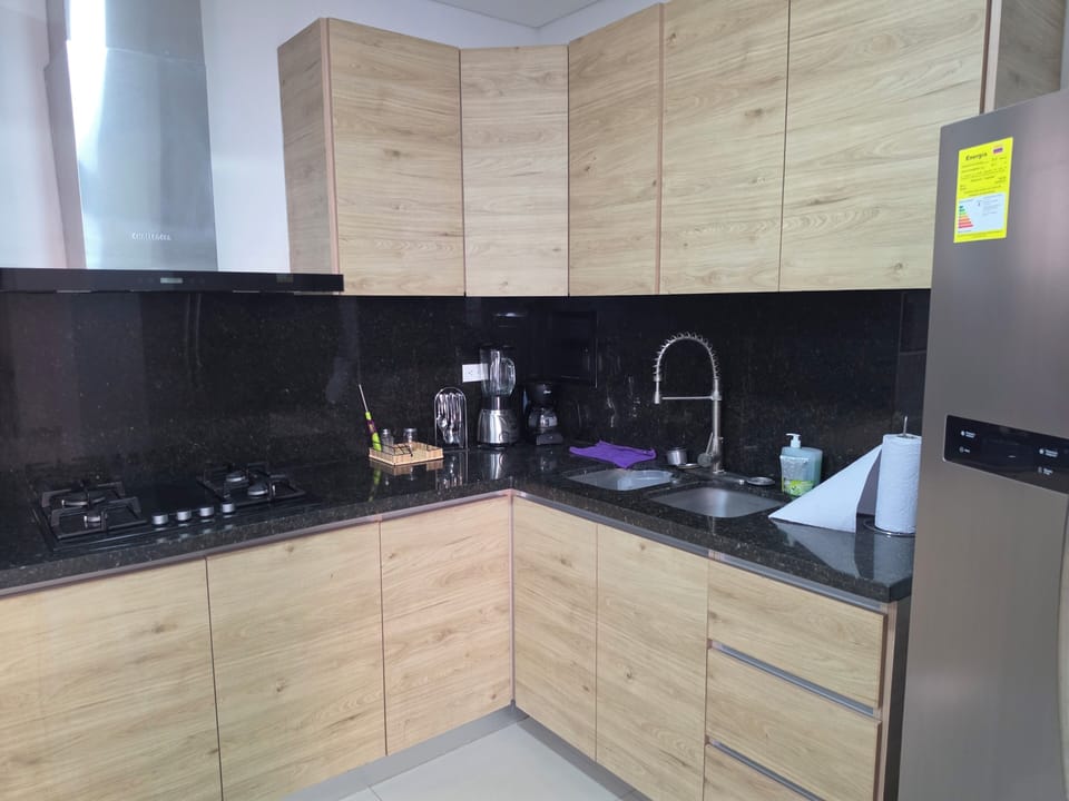 Sleek L-shaped kitchen with granite, gas cooktop, pull-down faucet, large fridge