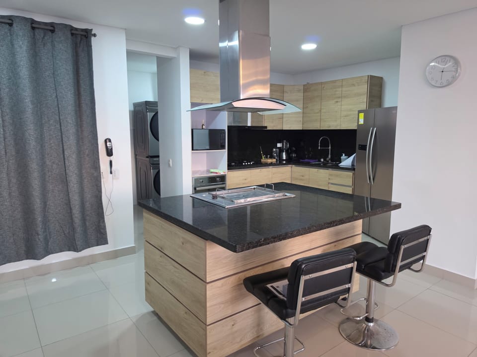 Sleek kitchen with island, bar seating, stainless appliances + laundry