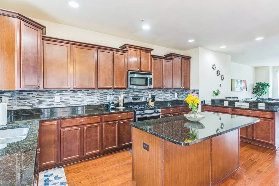 Spacious modern Kitchen featuring rich wooden cabinets, sleek granite countertops, a large island, and stainless steel appliances makes it easy to prep your food. 