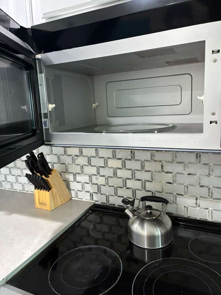 Modern kitchen with sleek cooktop, microwave, and stylish tile backsplash