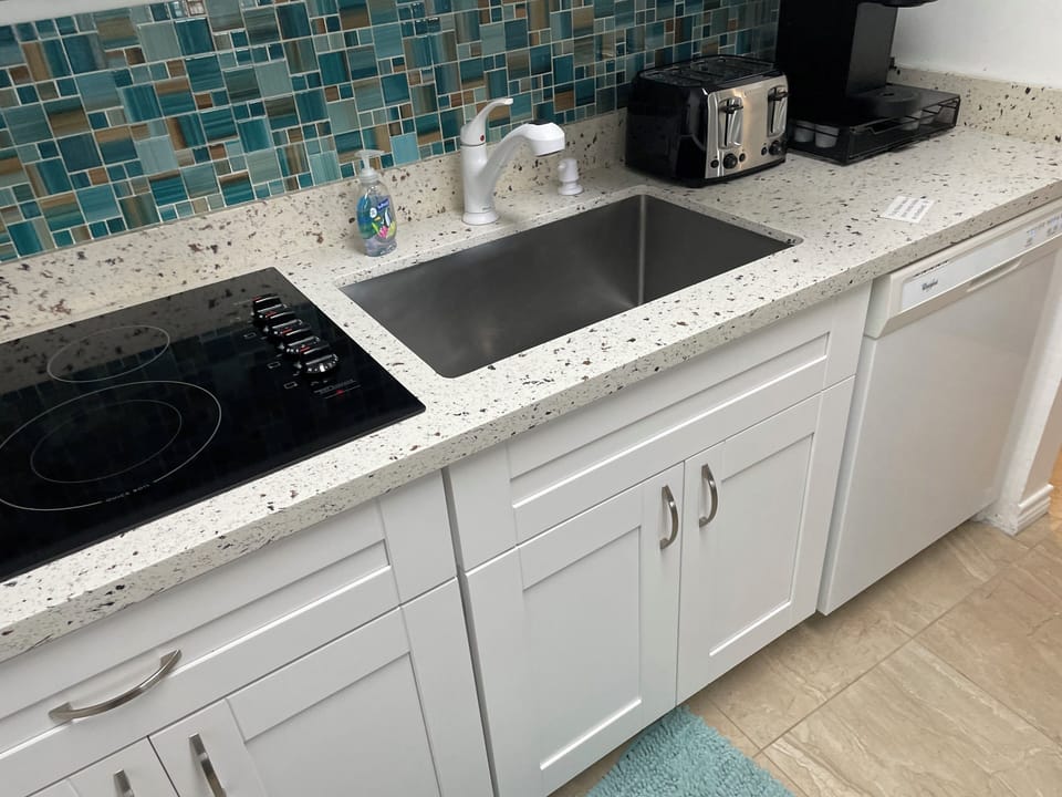 Bright modern kitchen with quartz counters, mosaic backsplash, and coffee station