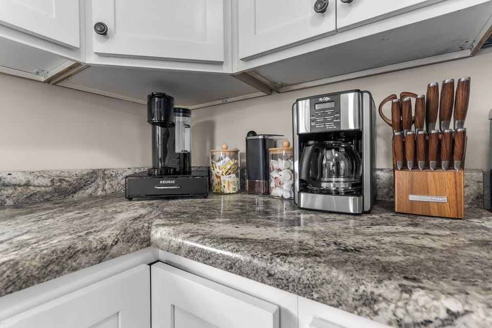 Coffee lovers corner. Stocked with a Keurig & drip coffee maker. Additional stocked items include: coffee pods/grounds, creamer & sugar.