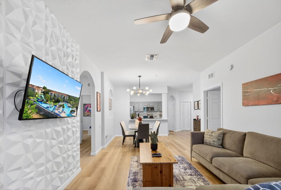 Bright open living space with modern kitchen, dining area, and stylish accent wall