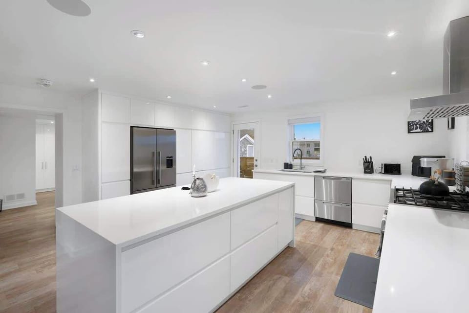 Bright, spacious kitchen featuring a large island, modern appliances including a double-door refrigerator, dishwasher, gas stove, toaster, and ample storage.