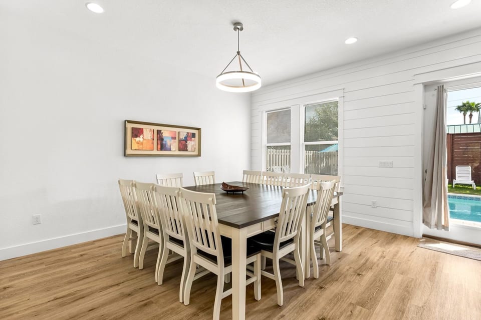 1st Floor-Dining room with seating for 12, sliding glass doors to the pool, and open flow to the living room and kitchen—ideal for shared meals and celebrations.