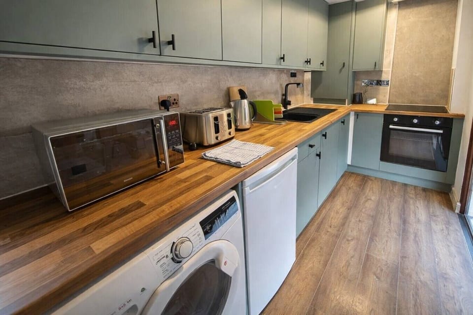 Fully equipped modern kitchen with oven, hob, microwave, toaster, kettle, fridge, and washing machine. Stylish design with wooden worktops and plenty of space, ideal for cooking during your Liverpool city centre stay.