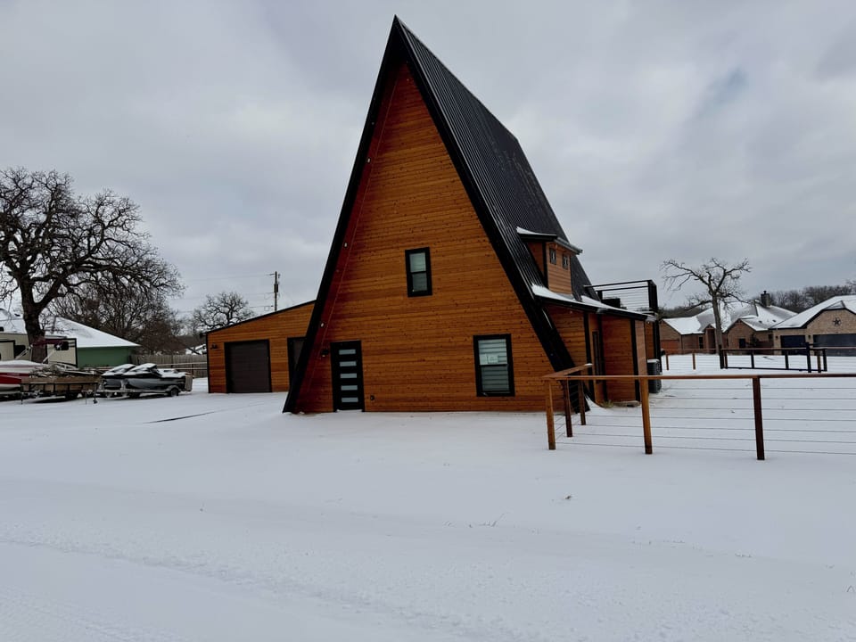 Striking modern A-frame cabin with warm wood exterior and snowy charm