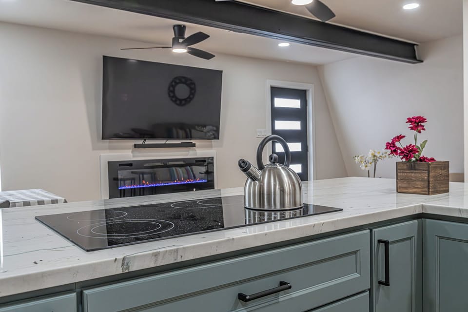 Modern open-concept kitchen with waterfall island, fireplace, and TV lounge