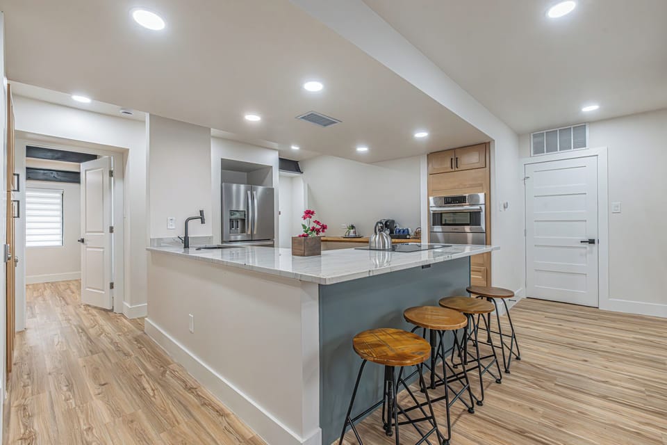 Bright modern kitchen with large island seating for four, premium refrigerator featuring an integrated ice and water dispenser