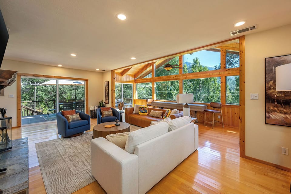 Sun-filled great room with forest views and access to a covered deck