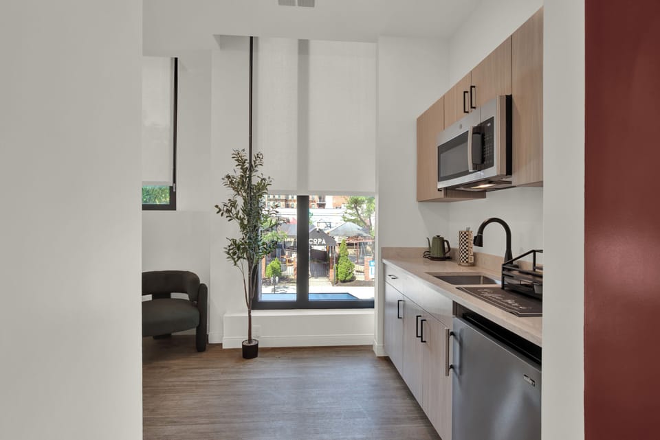 Bright modern kitchenette with tall windows and sleek finishes
