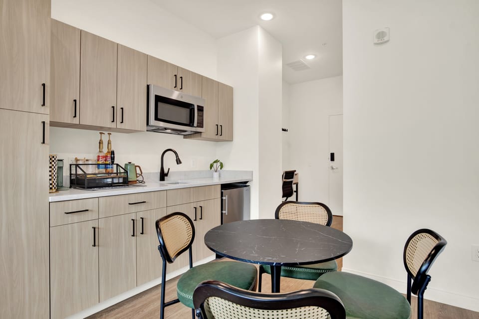 Modern kitchenette with dining table, mini fridge, and sleek finishes