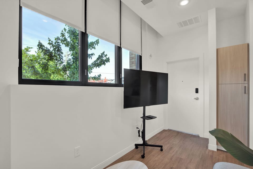 Bright modern space with large windows, leafy views, and movable TV