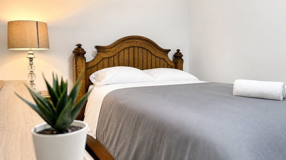 Cozy bedroom with warm lighting, plush bedding, and classic wood accents