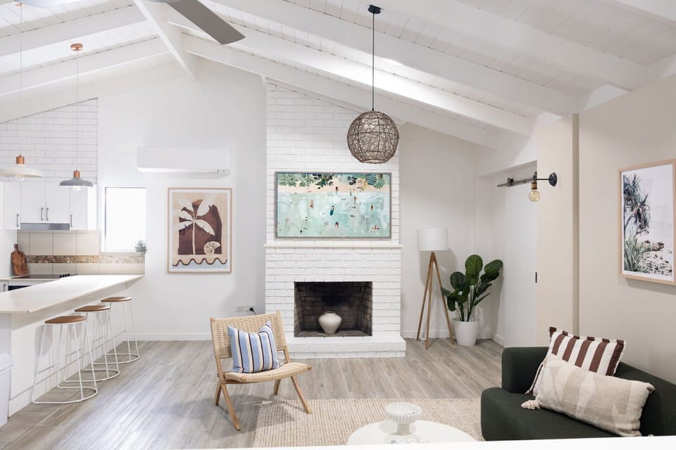 Bright vaulted living room with fireplace, bar seating, and coastal style