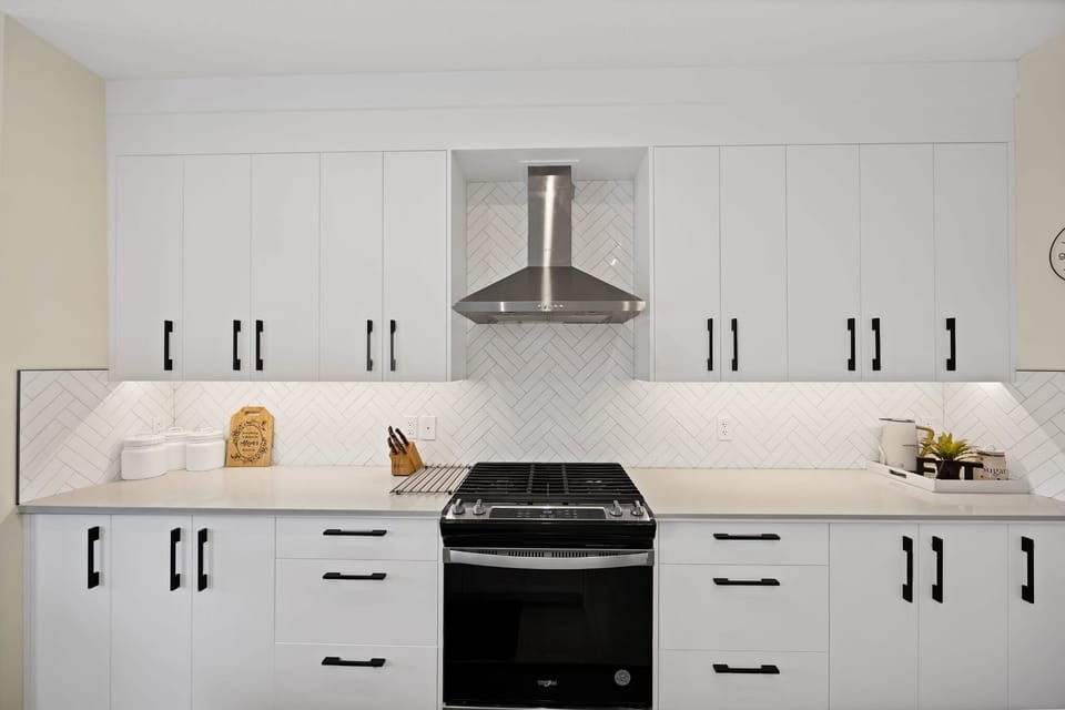 Bright modern kitchen with gas range, stylish backsplash, and ample storage