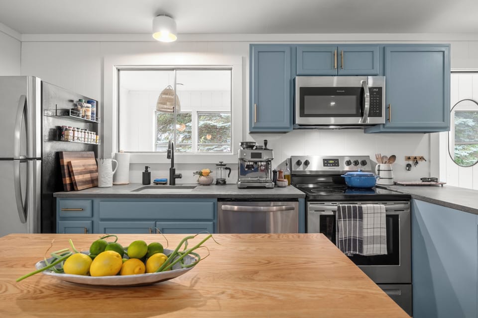 Bright modern kitchen with blue cabinets, island, and stainless appliances