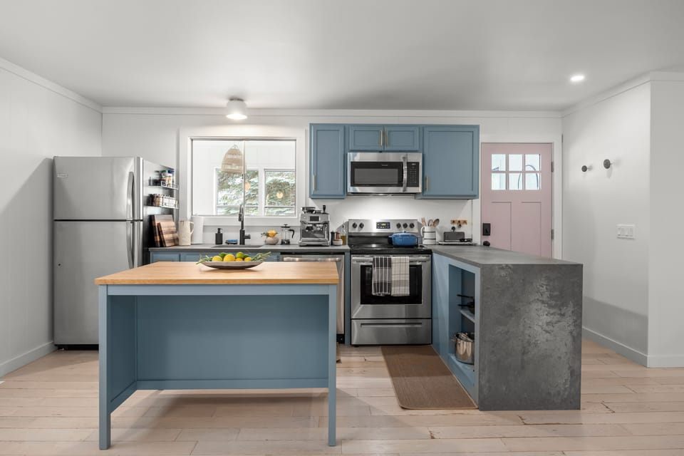 Bright modern kitchen with blue cabinets, island, and stainless appliances