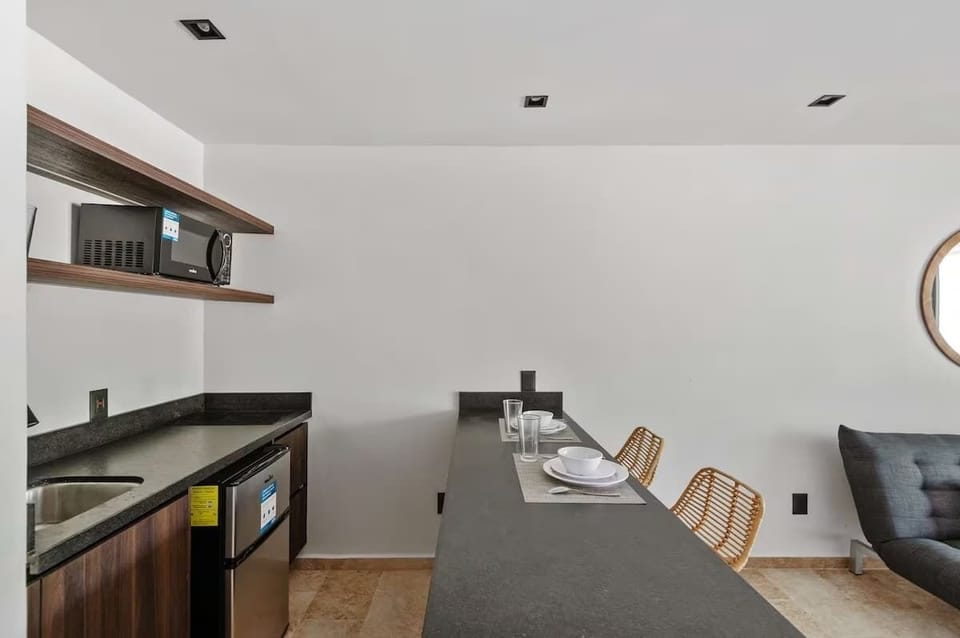 Fully equipped modern kitchenette. Features a sleek induction cooktop, microwave, refrigerator, and essentials for preparing light meals.