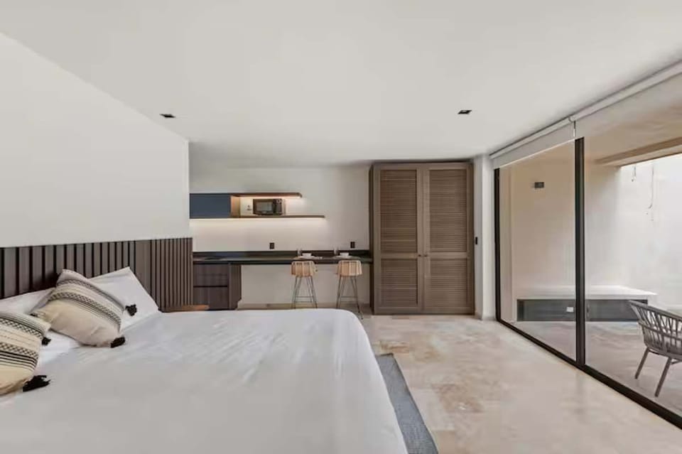 Expansive studio view showcasing the King bed, workspace bar, large wardrobe, and direct access to the private plunge pool terrace. Fully air-conditioned.