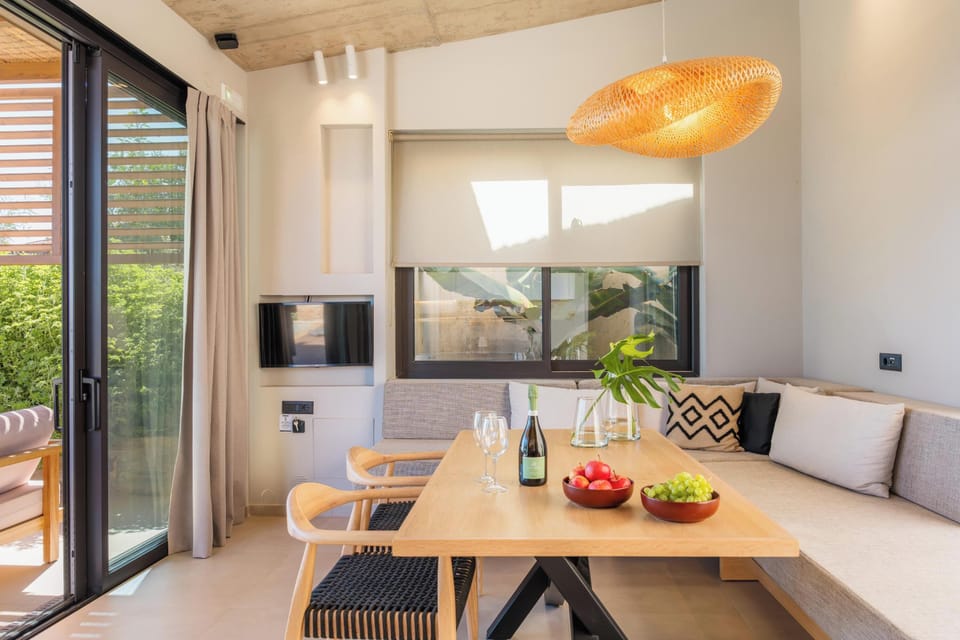 The living room features a 32” Smart TV, a corner sofa, and a dining table, along with a selection of board and card games for entertainment.