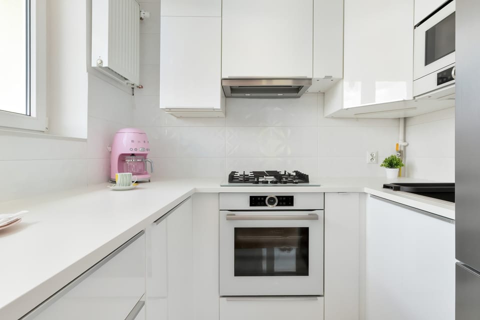 A sleek white kitchen with modern cabinetry, built-in oven, and ample countertop space. Clean lines and bright finishes create a contemporary look.