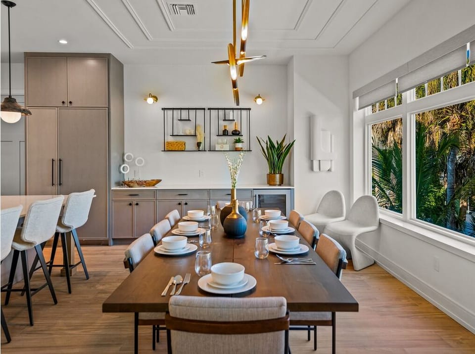 Gather around your beautiful dining table in this bright, open-concept space where modern design meets tropical views. The chef's kitchen flows seamlessly into the dining area, creating the perfect setting for memorable meals together.