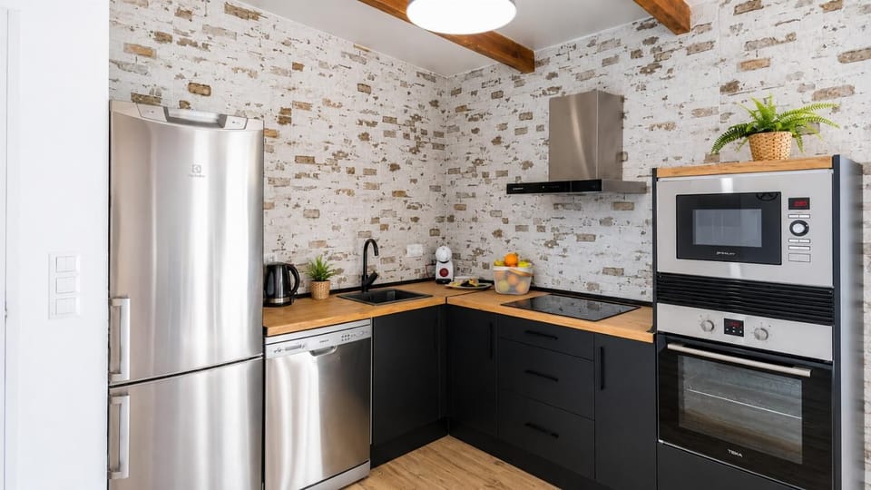 Modern fully equipped kitchen with black cabinetry, wooden worktops, and stylish rustic wall details.