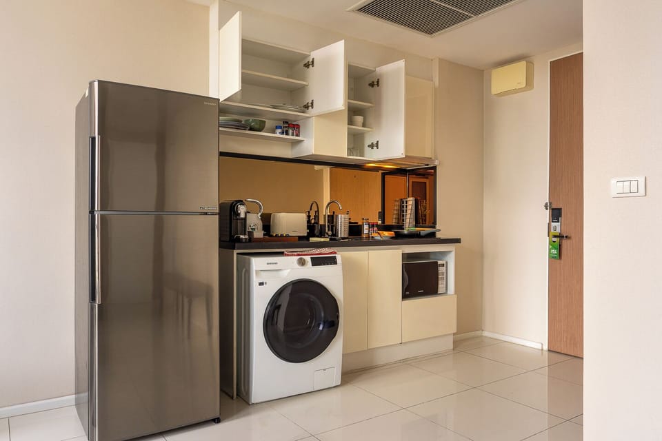 Bright kitchenette with washer, full fridge, and smart storage