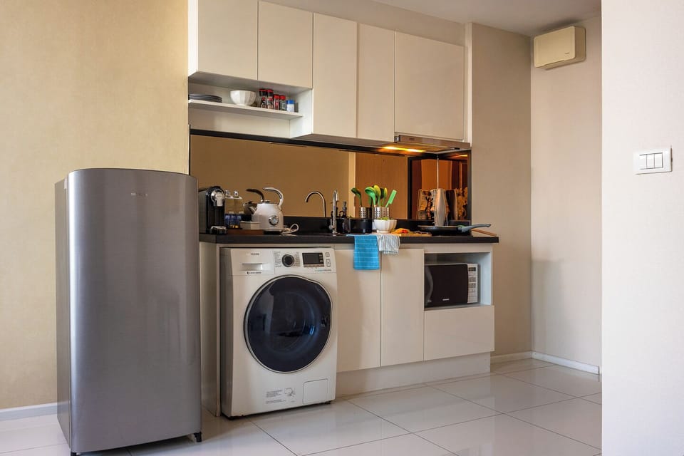 Compact modern kitchenette with washer, fridge, and cooking essentials