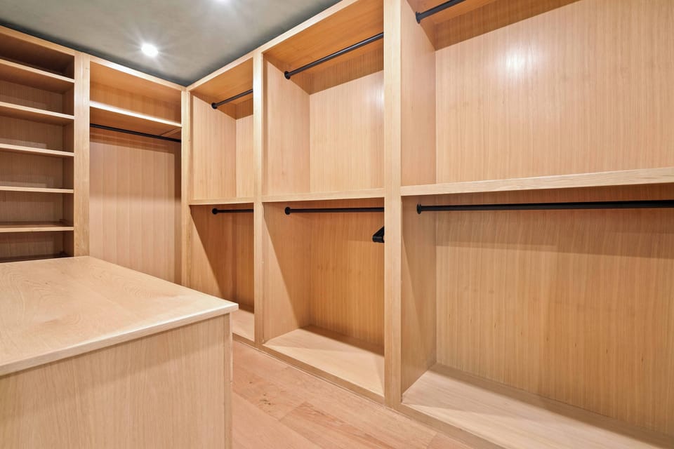 Master suite walk-in closet with custom built-in wood shelving, hanging rods, and center island