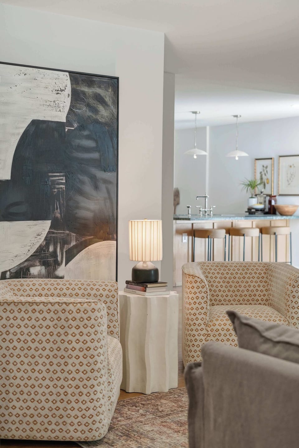 Accent seating area with patterned armchairs, large abstract canvas, and view through to kitchen island