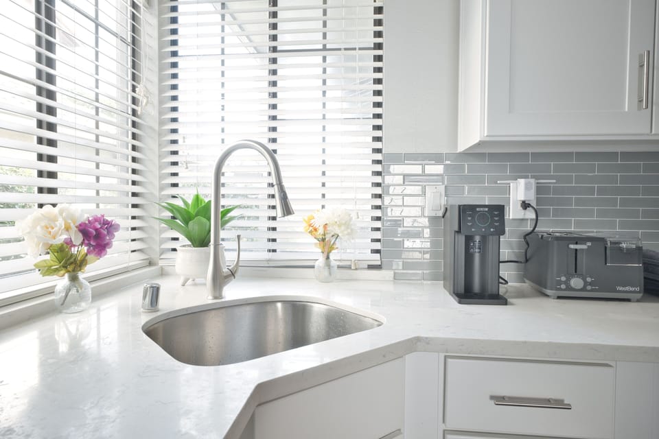 Sunlit kitchen with quartz tops, coffee station, and sleek subway tile.