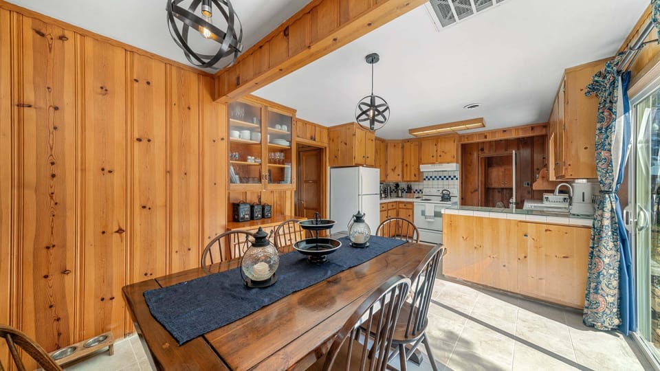 Sliding door, dining table, oven, and refrigerator frame the dining area.