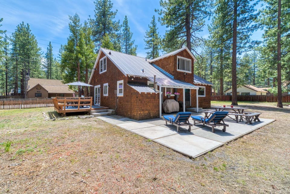 Exterior view with trees, deck, patio, and umbrella.