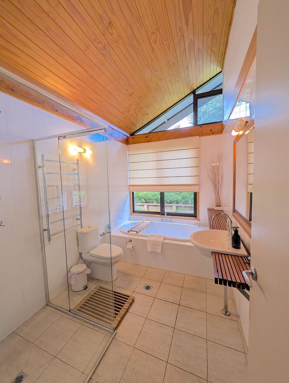 Main bathroom with soaker bath beneath a garden window, separate shower, heated towel rail and timber ceiling. Shared between bedrooms two and three.