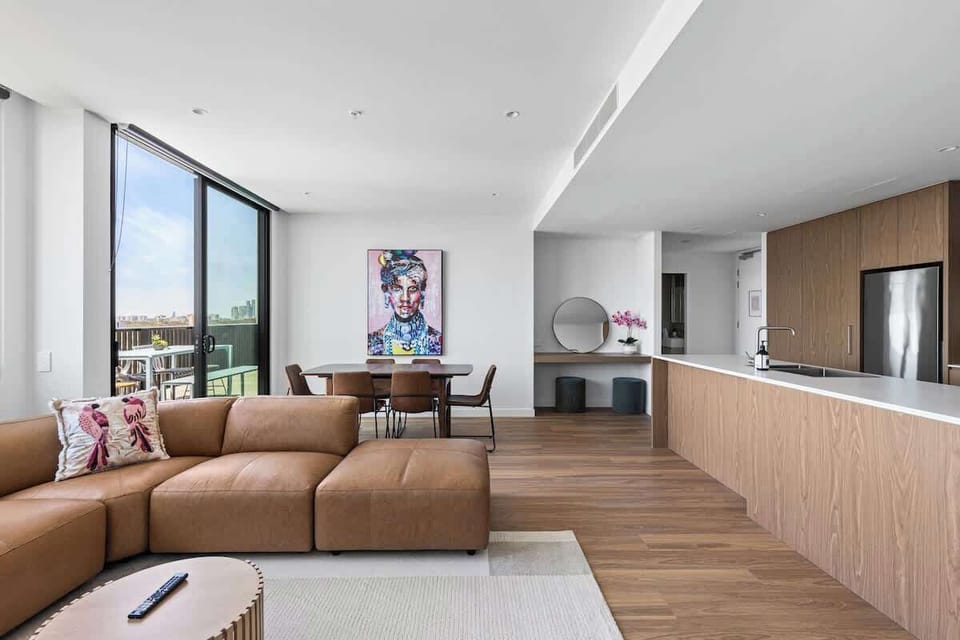 Bright open-plan living and dining area with comfortable lounge seating, city views and space to relax, dine and unwind together.