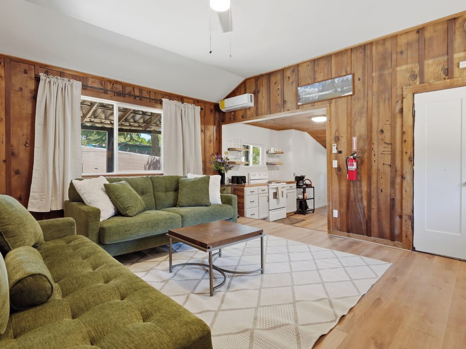 Cozy wood-paneled lounge with plush seating and open kitchenette